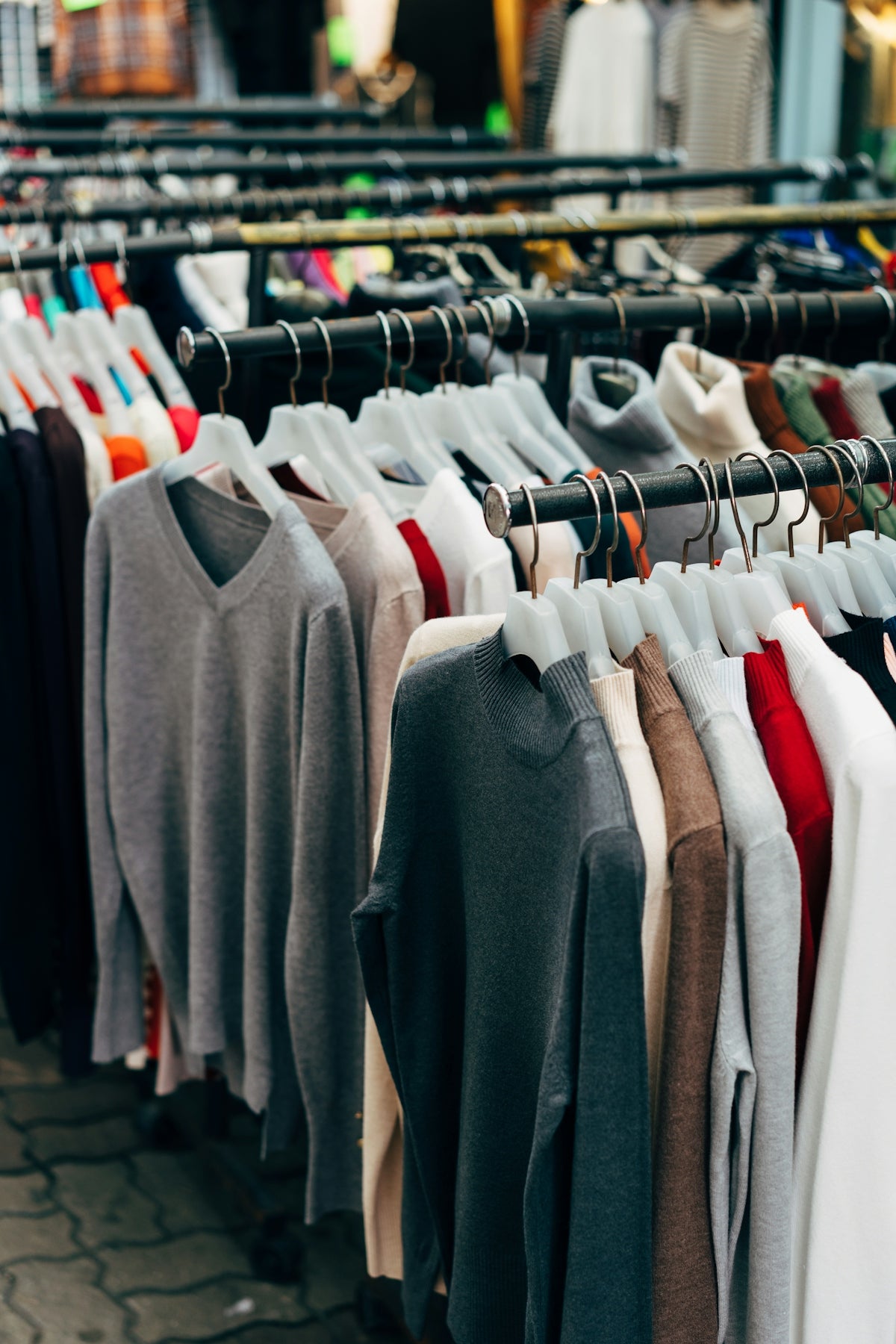 Rows of colorful sweaters hanging on hangers on a clothing rack